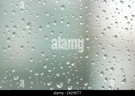 Regentropfen auf einer Fensterscheibe bei regnerischem Wetter Stockfoto