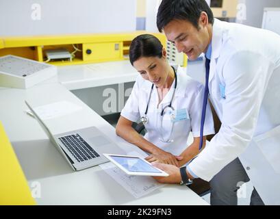 Verfolgung der Patientenfortschritte in Echtzeit. Ein medizinisches Team durchläuft eine Patientenakte auf einer Tablette. Stockfoto
