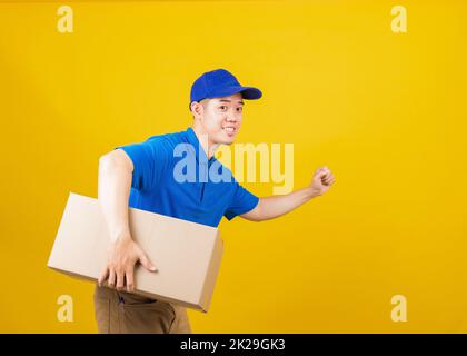 Logistisches Standlächeln mit blauem T-Shirt und Kappe, Uniform, die Paketkiste hält Stockfoto