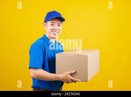 Lieferung glücklicher Mann logistisch stehend lächelt er trägt ein blaues T-Shirt und eine Kappe Uniform Paketkiste Stockfoto