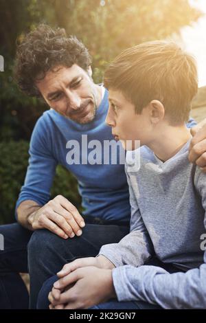 Geben seinem Sohn einige väterliche Ratschläge. Ein Vater und Sohn haben ein Herz zu Herz im Hinterhof. Stockfoto