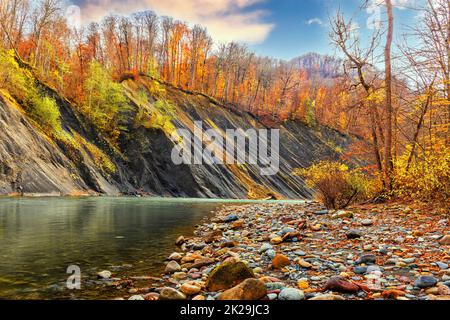 Herbstlandschaft eines Flusses, der zwischen den Bergen fließt Stockfoto