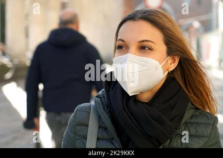 Nahaufnahme einer legeren Frau, die in der Stadtstraße mit einer schützenden KN95 FFP2-Gesichtsmaske zur Seite geht Stockfoto