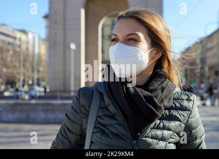 Schöne Frau in der Stadt Straße trägt KN95 FFP2 Maske Schutz gegen Atemwegserkrankungen Blick zur Seite Stockfoto