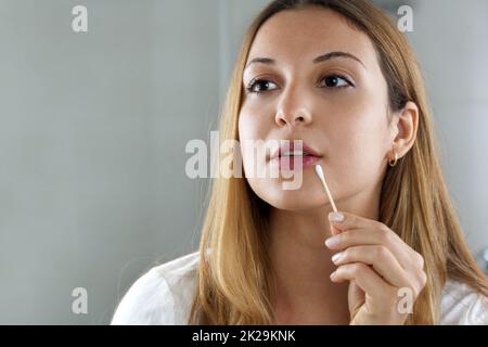 Nahaufnahme eines Mädchens, das sich zu Hause in den Spiegel schaut, mit umweltfreundlichen Wattestäbchen, um Make-up-Flecken zu entfernen. Nachhaltiges, kunststofffreies, biologisch abbaubares Konzept. Stockfoto