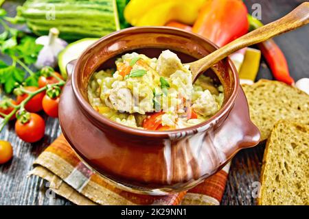 Reis mit Hühnchen und Gemüse im Topf auf Holzbrett Stockfoto