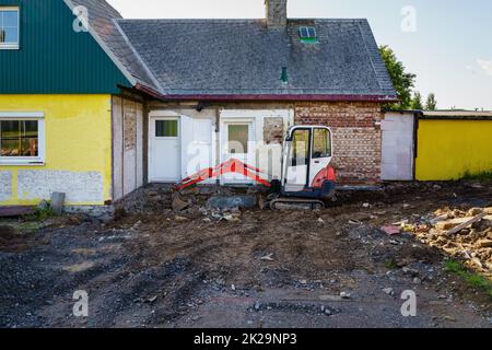 Das Familienhaus wird mit Hilfe eines Baggers wieder aufgebaut. Graben der Ziegel-und Betonfundament. Stockfoto