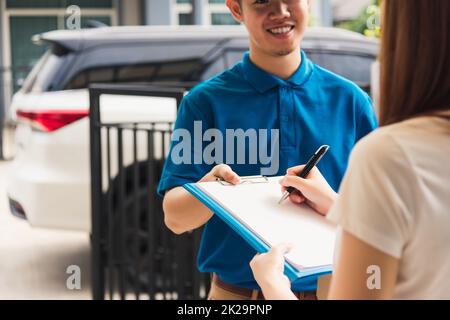 Eine Frau, die die Lieferung unterschreibt, holt ihr Paket vom Service-Kurierdienst Stockfoto