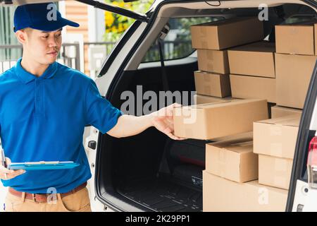 Der man-Kurier in Uniform hält Dokumente in der Zwischenablage, Checkliste Paketpostkartons Stockfoto