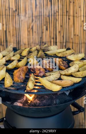 Mariniertes Huhn mit Kartoffeln auf einem Gartengrill Stockfoto