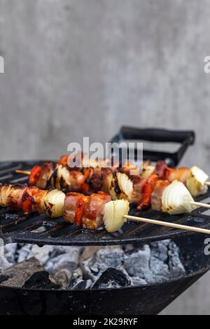 Spieß mit Paprika Zwiebel und geräuchertes Schweinefleisch auf einem Gartengrill Stockfoto