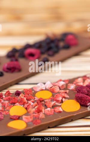 Verschiedene Arten von Schokolade mit getrockneten Früchten auf einem Holzbrett Stockfoto