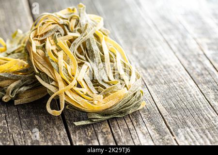 Eiernudeln. Nudeln mit Spinatgeschmack nisten auf einem Holztisch. Stockfoto