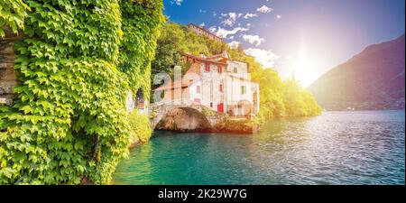 Die historische Steinbrücke der Stadt Nesso und der malerische Panoramablick am Seeufer mit Sonnenschein Stockfoto