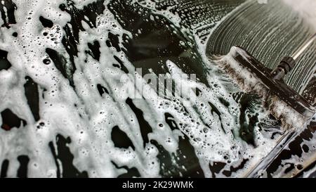 Widshield eines Autos in selbst gewaschen werden dienen Carwash, Pinsel, Anschläge in white Shampoo und Schaum auf Glas. Stockfoto