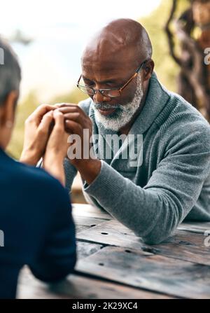 Paare, die zusammen beten, bleiben zusammen. Ausgeschnittene Aufnahme eines älteren Paares, das im Freien betet. Stockfoto