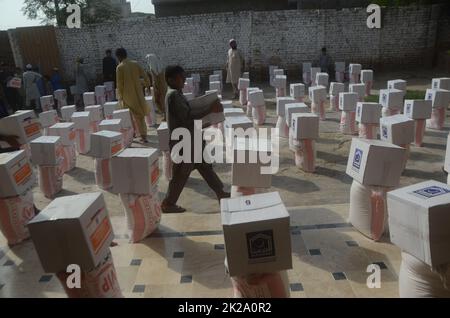 Peshawar, Khyber Pakhtunkhwa, Pakistan. 22. September 2022. Die von Überschwemmungen betroffenen Menschen erhalten von der Al Khidmat Foundation im Bezirk Nowshera, Dorf Garhi Momin, Provinz Khyber Pakhtunkhwa Hilfsgelder. (Bild: © Hussain Ali/Pacific Press via ZUMA Press Wire) Stockfoto