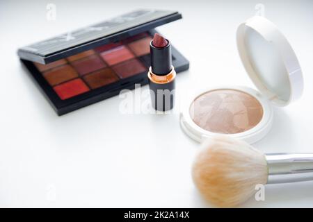 Weißes Gesichtspulver und Bronzer, schwarze Verpackung mit Lidschatten, Lippenstift und Bürste auf weißem Hintergrund Stockfoto