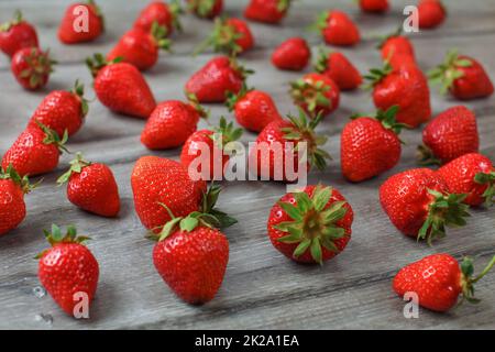 Rote reife Erdbeeren auf grau Holz Schreibtisch verschüttet. Stockfoto