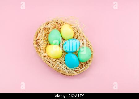 Korb mit bunten Ostereiern auf pinkfarbenem Hintergrund Stockfoto