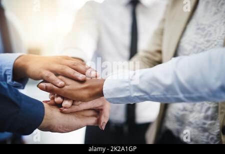 Es ist schwer, jemanden zu schlagen, der nicht aufgeben wird. Ausgeschnittene Aufnahme einer Gruppe von Geschäftsleuten, die ihre Hände in Einheit zusammengelegt haben. Stockfoto