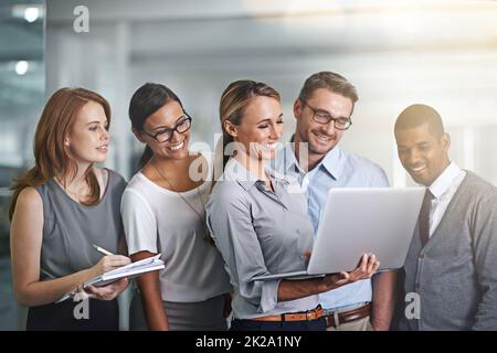 Gemeinsam erreichen alle mehr. Aufnahme eines Geschäftsteams, das zusammen an einem Laptop arbeitet. Stockfoto