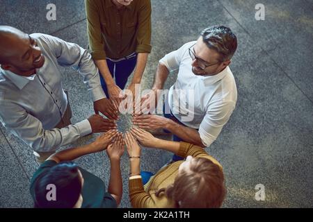 Die Aufgabe als Einheit zu erledigen. Eine Gruppe von Kollegen, die sich bei der Arbeit solidarisch in die Hände schlossen, wurde aus einem Blickwinkel aufgenommen. Stockfoto