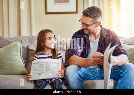 Eltern zu sein ist mein Lieblingsjob. Aufnahme eines Vaters und einer Tochter beim Lesen der Zeitung. Stockfoto