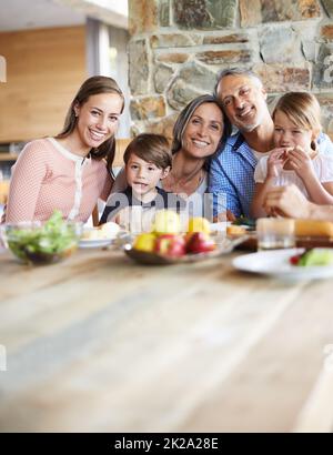 Wertvolle Momente mit den Enkelkindern. Ein Porträt einer glücklichen, generationsübergreifenden Familie, die an einem Tisch sitzt und zusammen zu Mittag gegessen hat. Stockfoto