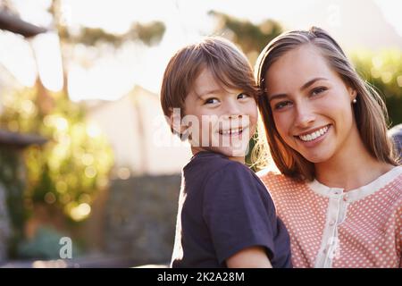 Die Hölle wird schon zu lange wachsen. Porträt einer glücklichen jungen Mutter und ihres entzückenden Sohnes, der draußen im Garten steht. Stockfoto