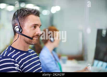 Professionelle Kundenbetreuung. Aufnahme eines jungen Geschäftsmanns, der ein Headset in einem Büro trägt. Stockfoto