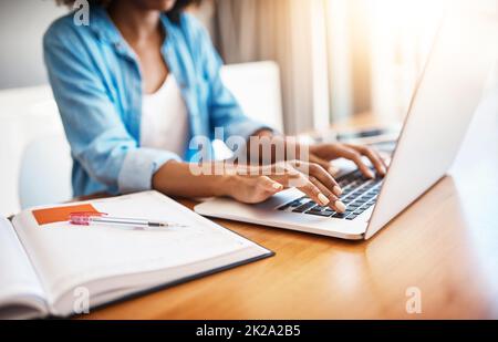 Sie kennt sich definitiv im Internet aus. Aufnahme einer jungen Frau, die zu Hause an ihrem Laptop arbeitet. Stockfoto