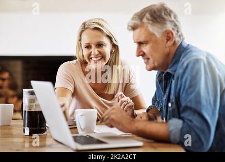 Das Internet macht alles andere einfacher. Ausgeschnittene Aufnahme eines reifen Paares, das zusammen einen Laptop benutzt. Stockfoto