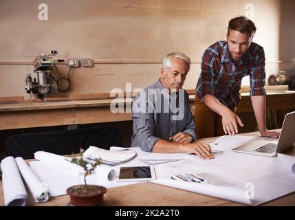 Sein ganzes Wissen weitergeben. Ausgeschnittene Aufnahme eines Vaters und eines Sohnes, die in ihrer Werkstatt zusammenarbeiten. Stockfoto