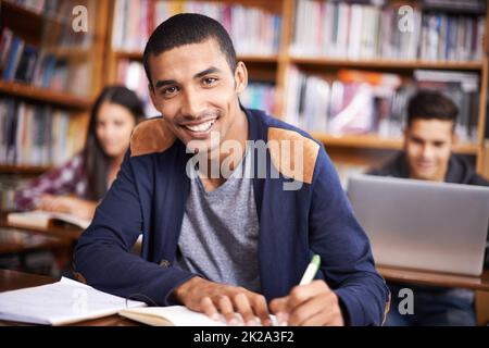 Hes ein so fleißiger Student. Beschnittenes Porträt eines hübschen jungen Studenten, der fleißig in seinem Klassenzimmer arbeitet. Stockfoto