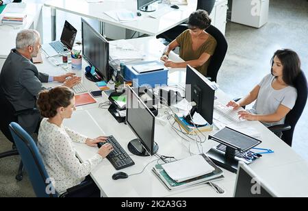 Erfolg für ein Projekt nach dem anderen. Aufnahme einer Gruppe von Mitarbeitern, die an ihren Arbeitsplätzen in einem Büro sitzen. Stockfoto