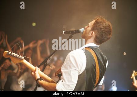 Musik aus dem Herzen. Aufnahme eines Frontmanns in einer Band, der auf der Bühne singt. Stockfoto