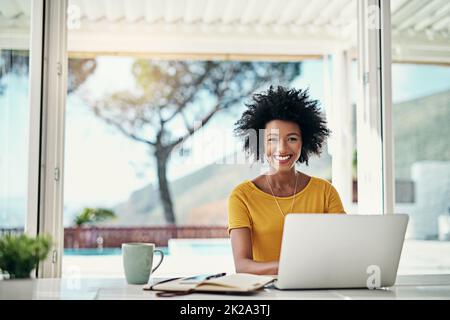 Du musst für den Erfolg arbeiten. Das verkürzte Porträt einer attraktiven jungen Frau, die zu Hause an ihrem Laptop arbeitet. Stockfoto