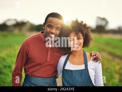 Unsere Farm blüht. Beschnittenes Porträt eines liebevollen jungen Paares, das auf ihrem Bauernhof steht. Stockfoto