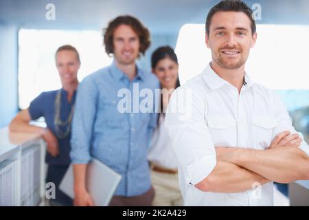 Wir scheuen uns nie vor harter Arbeit. Eine kurze Aufnahme von vier Mitarbeitern, die im Büro stehen. Stockfoto