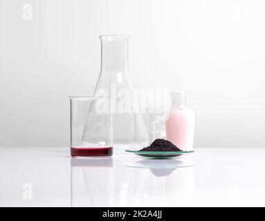 Kosmetische chemische Inhaltsstoffe auf dem weißen Labortisch. Kaliumpermanganat, flüssig, KMnO4 ml, Beauty Care Cream neben Becher und erlenmeyerkolben. Stockfoto