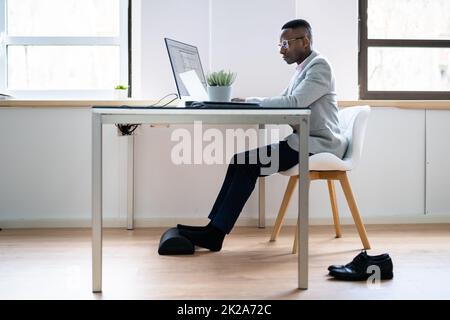 Arbeiter, Der Fußstützen Verwendet, Um Rückenschmerzen Zu Reduzieren Stockfoto