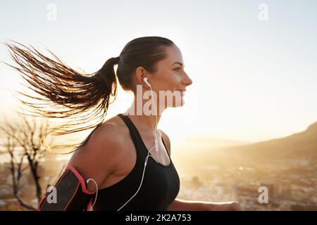 Diese Endorphine treten ein. Aufnahme einer jungen Frau, die beim Laufen Musik hört. Stockfoto