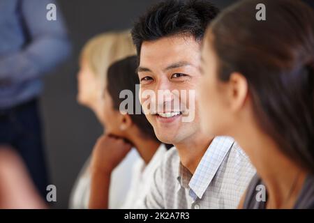 Eine Idee, die sich von der Sache abhebt. Aufnahme eines asiatischen Mannes, der mit seinen Kollegen an einem Tisch sitzt. Stockfoto