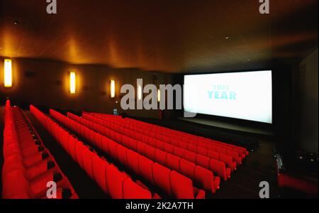 Licht, Kamera, Action. Ein leeres Kino oder Kino mit einer großen Leinwand und roten Sitzreihen. Stockfoto