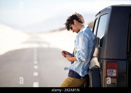 Ich brauche hier ein wenig Hilfe. Ein junger Mann, der für Pannenhilfe telefonieren soll. Stockfoto