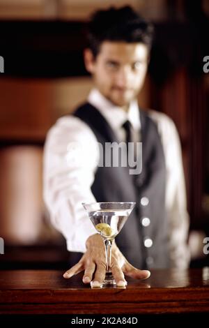 Für Sie. Porträt eines hübschen jungen Barkeepers, der einen Cocktail für einen Kunden mixt. Stockfoto