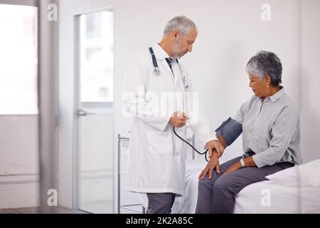 Eine Routineprüfung. Ein Arzt, der den Blutdruck eines reifen Patienten misst. Stockfoto