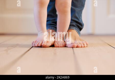 Gehen mit Mama. Nahaufnahme einer Mutter und ihren Kinderfüßen. Stockfoto