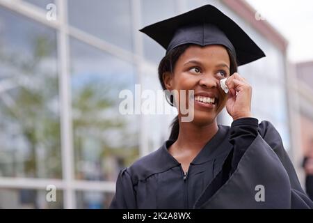 So viel, wofür man dankbar sein kann. Porträt einer schönen afrikanischen Studentin, die an ihrem Abschlusstag Freudentränen abwischt. Stockfoto